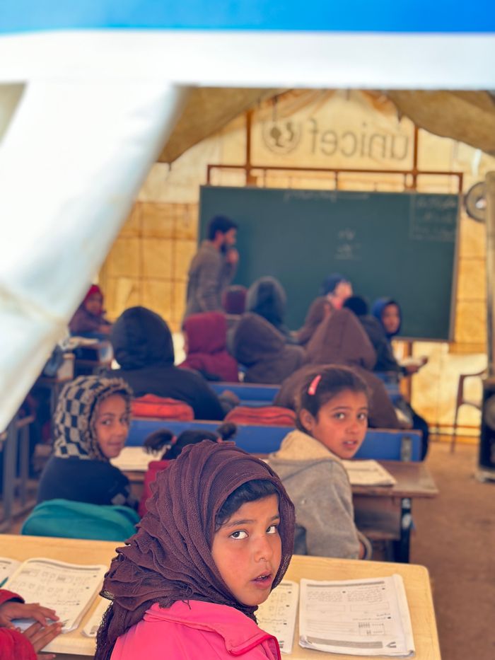Crafting Captivating Headlines: Your awesome post title goes here Children engaging in education inside a temporary classroom with a teacher and blackboard.