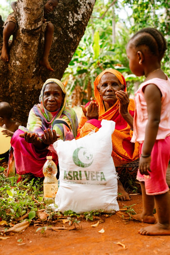 services-01 Elderly women and child receiving aid package in rural setting.
