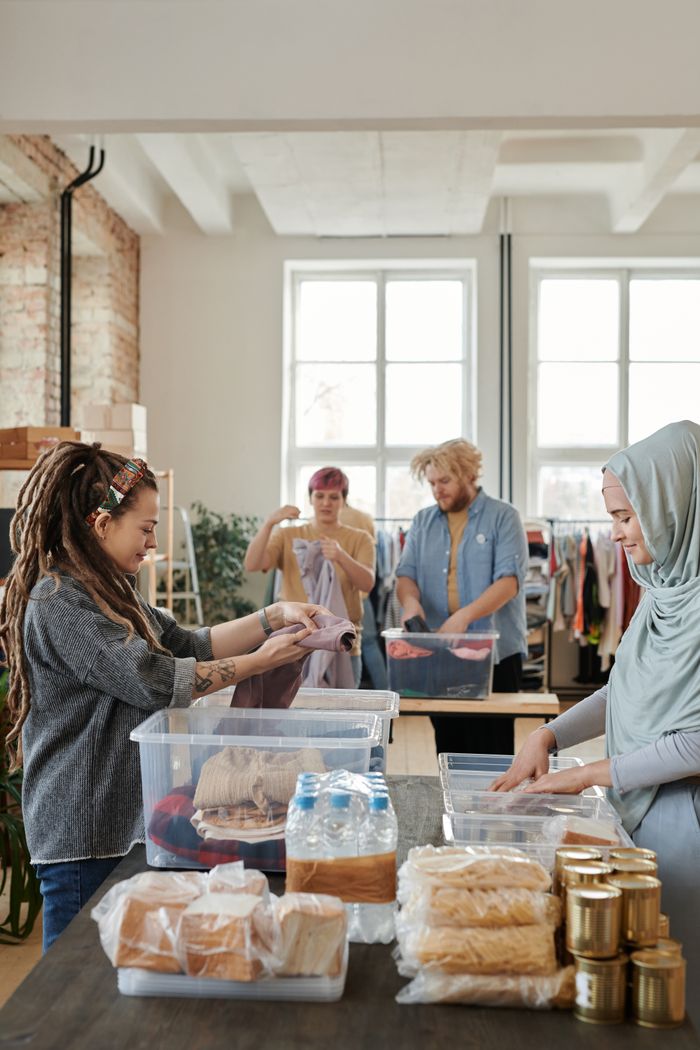 our-story A diverse group of volunteers sorting clothes and food items at an indoor donation center.