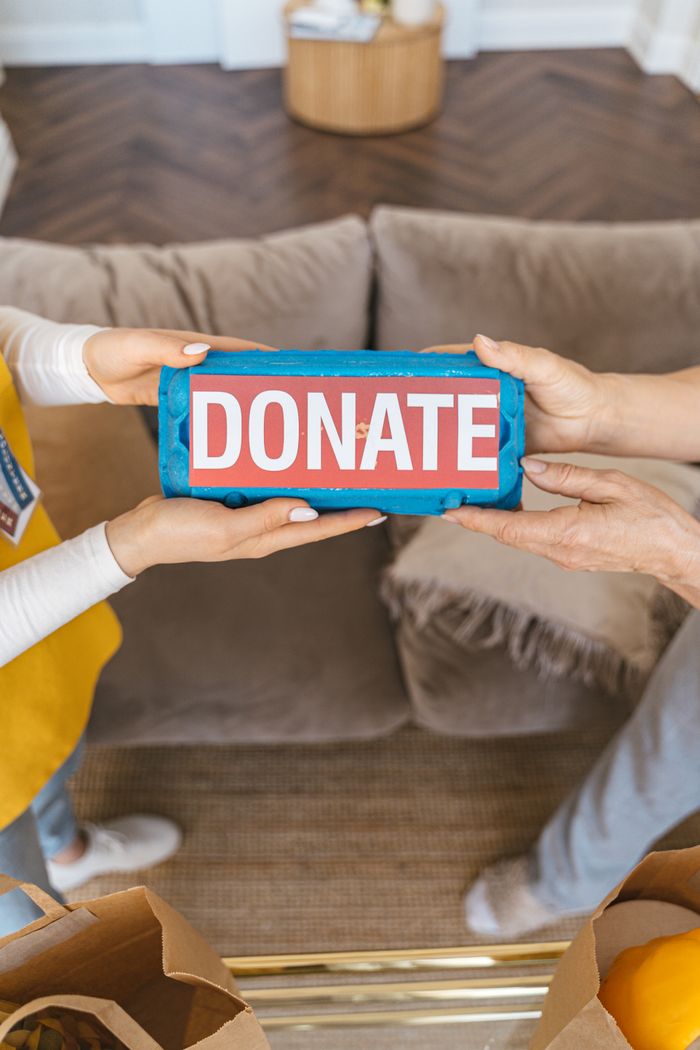 services-04 Two people exchanging a donation box indoors, symbolizing generosity and charity.